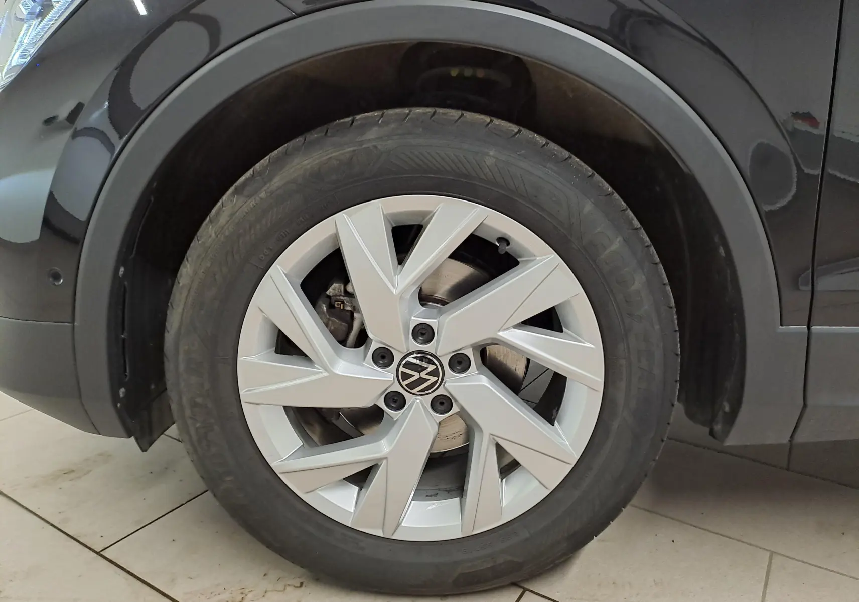 Gros plan sur la roue avant gauche du Volkswagen Tiguan noir intense, mettant en valeur la jante alliage et le pneu Goodyear.