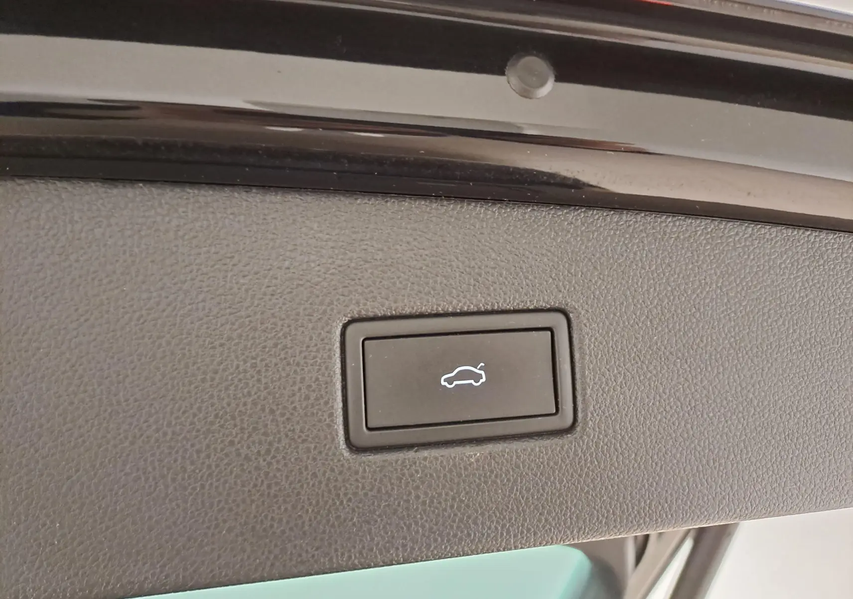 Bouton d'ouverture électrique du hayon sur la partie intérieure du coffre d'un Volkswagen Tiguan noir intense.
