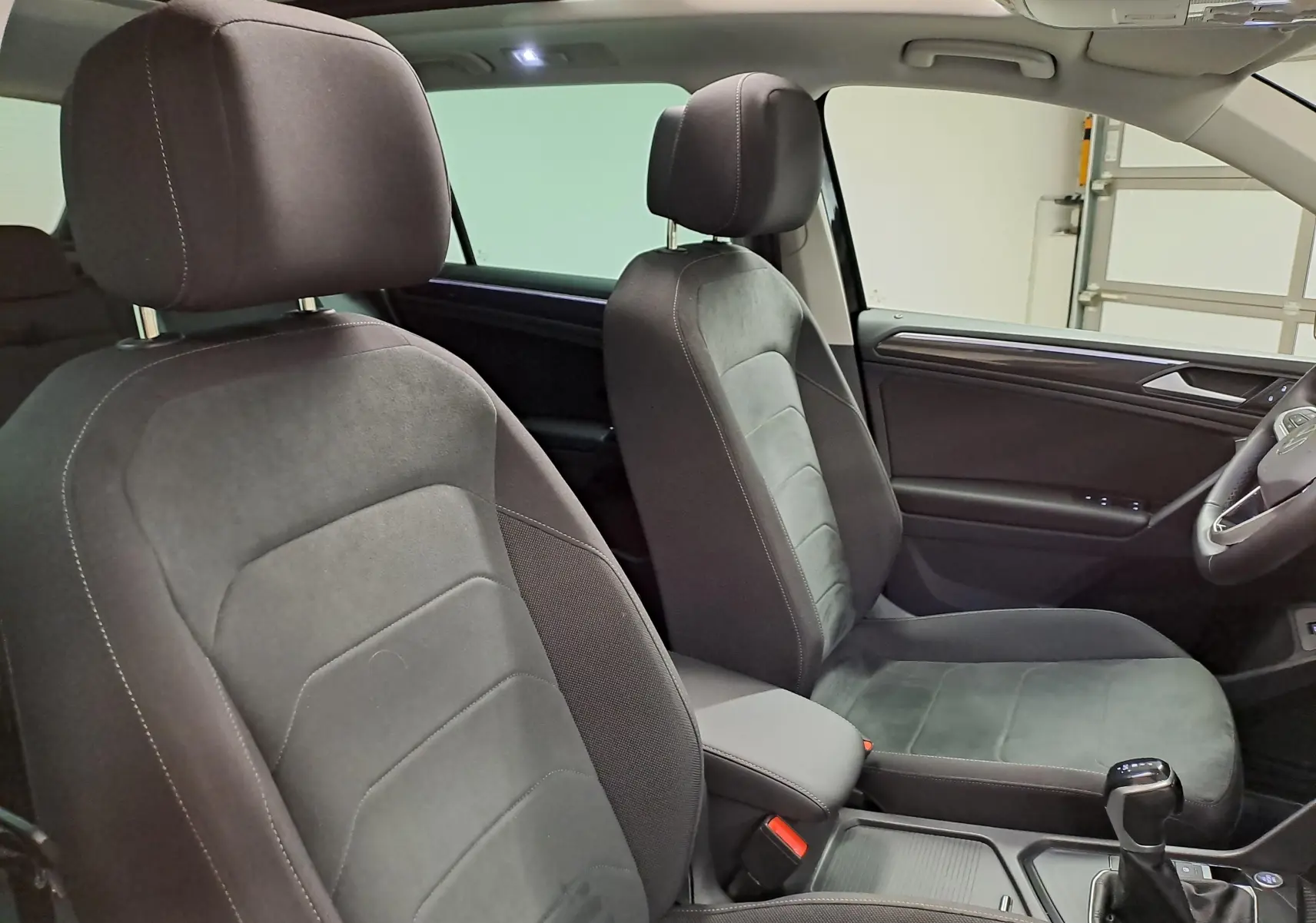 Vue intérieure du Volkswagen Tiguan 2022 montrant les sièges avant en tissu noir et la console centrale avec levier de vitesse.