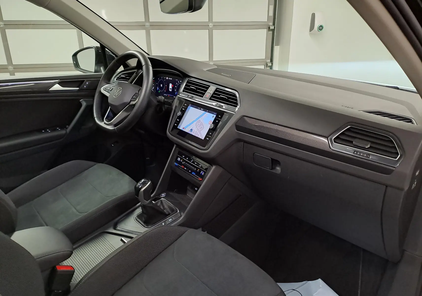 Vue intérieure côté conducteur du Volkswagen Tiguan 2022 avec tableau de bord noir et écran tactile central allumé.