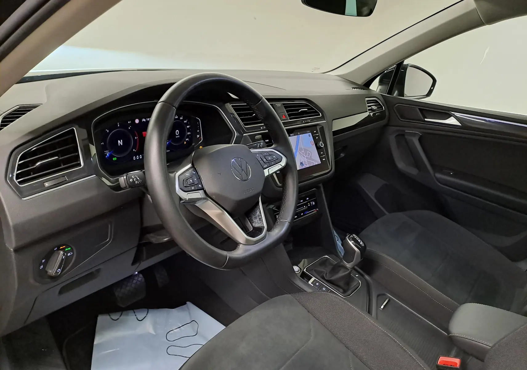Vue intérieure côté conducteur du Volkswagen Tiguan 2022, tableau de bord moderne avec écran tactile et volant multifonction.