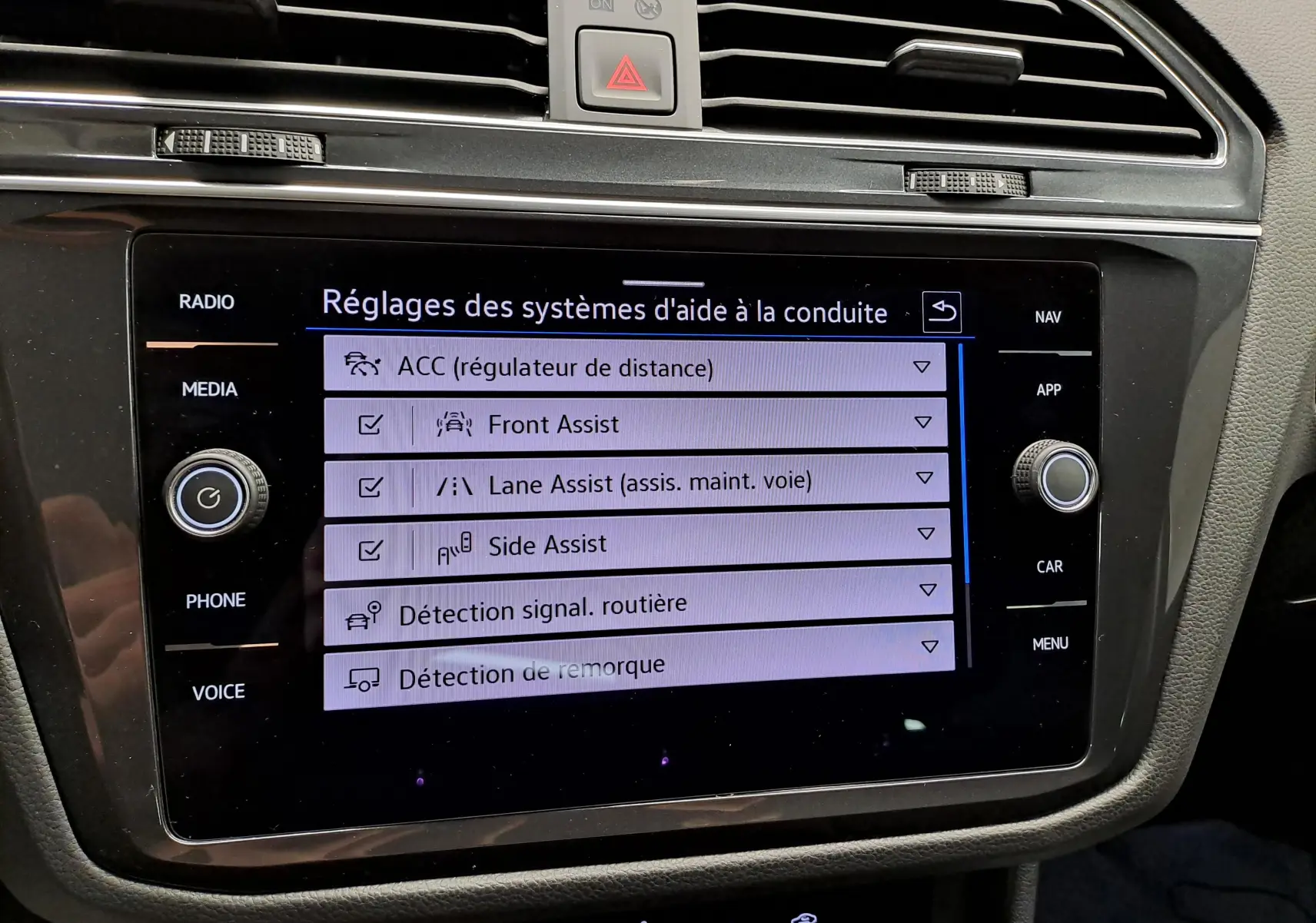 Écran tactile central du Volkswagen Tiguan 2022 affichant les réglages des aides à la conduite, intérieur noir.