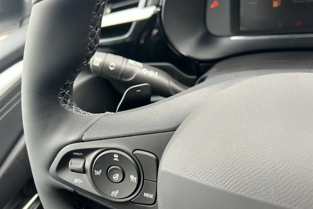 Gros plan sur le volant cuir noir de l’Opel Corsa Hybrid 110 e-DCT6, avec commandes multifonctions et bouton de chauffage.