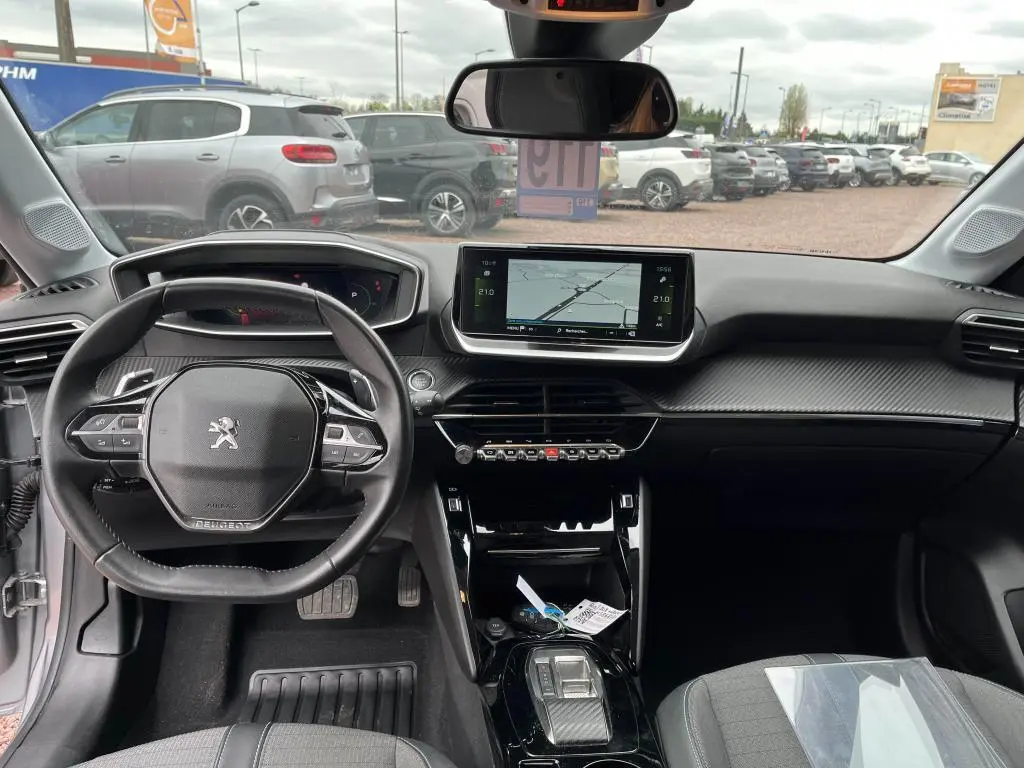 Vue intérieure avant de la Peugeot 208 gris clair 2022, avec tableau de bord moderne et écran tactile central 7 pouces.