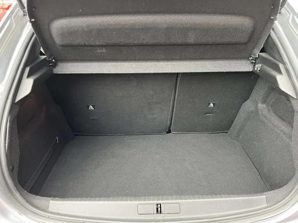 Coffre ouvert vu de l'arrière d'une Peugeot 208 gris clair, montrant un espace de chargement propre et vide.