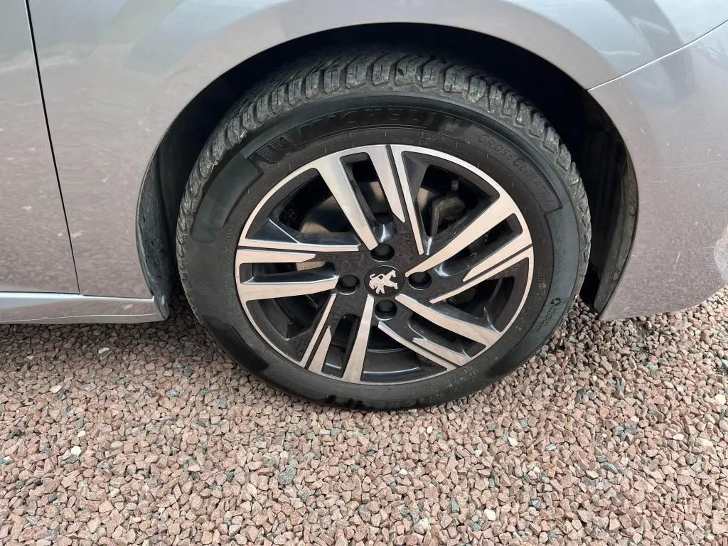 Gros plan sur la roue avant gauche gris clair d'une Peugeot 208 2022 avec jante alliage et pneu Michelin.