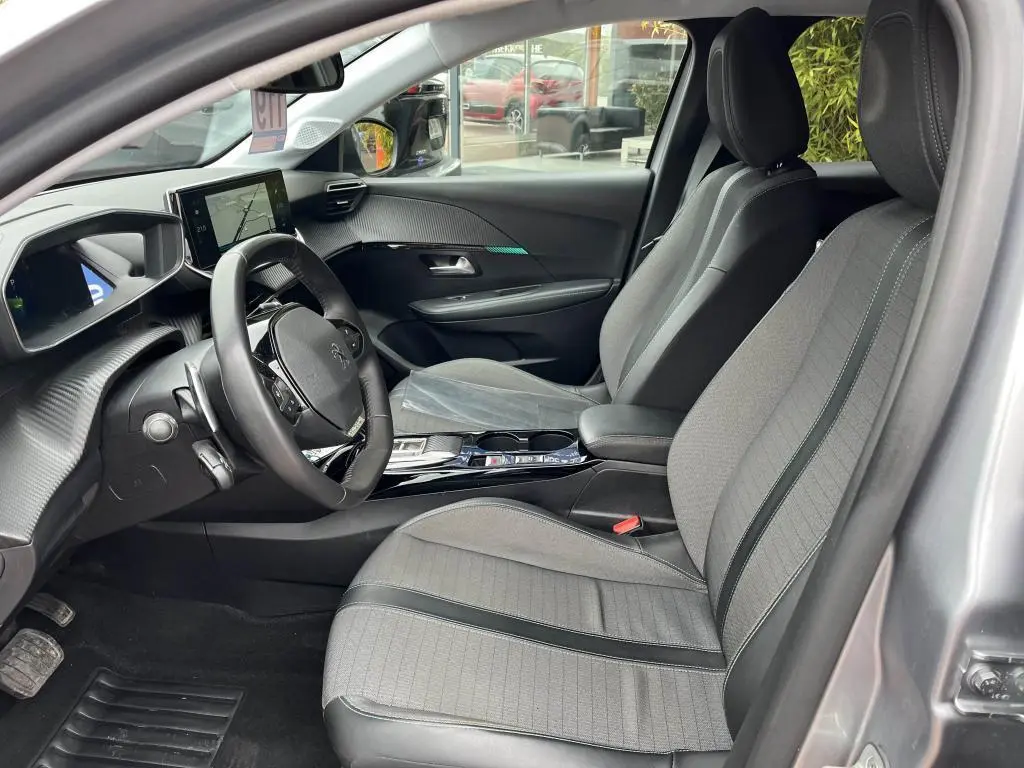 Intérieur avant gris clair de la Peugeot 208 2022, vue côté conducteur avec volant compact et écran tactile central.