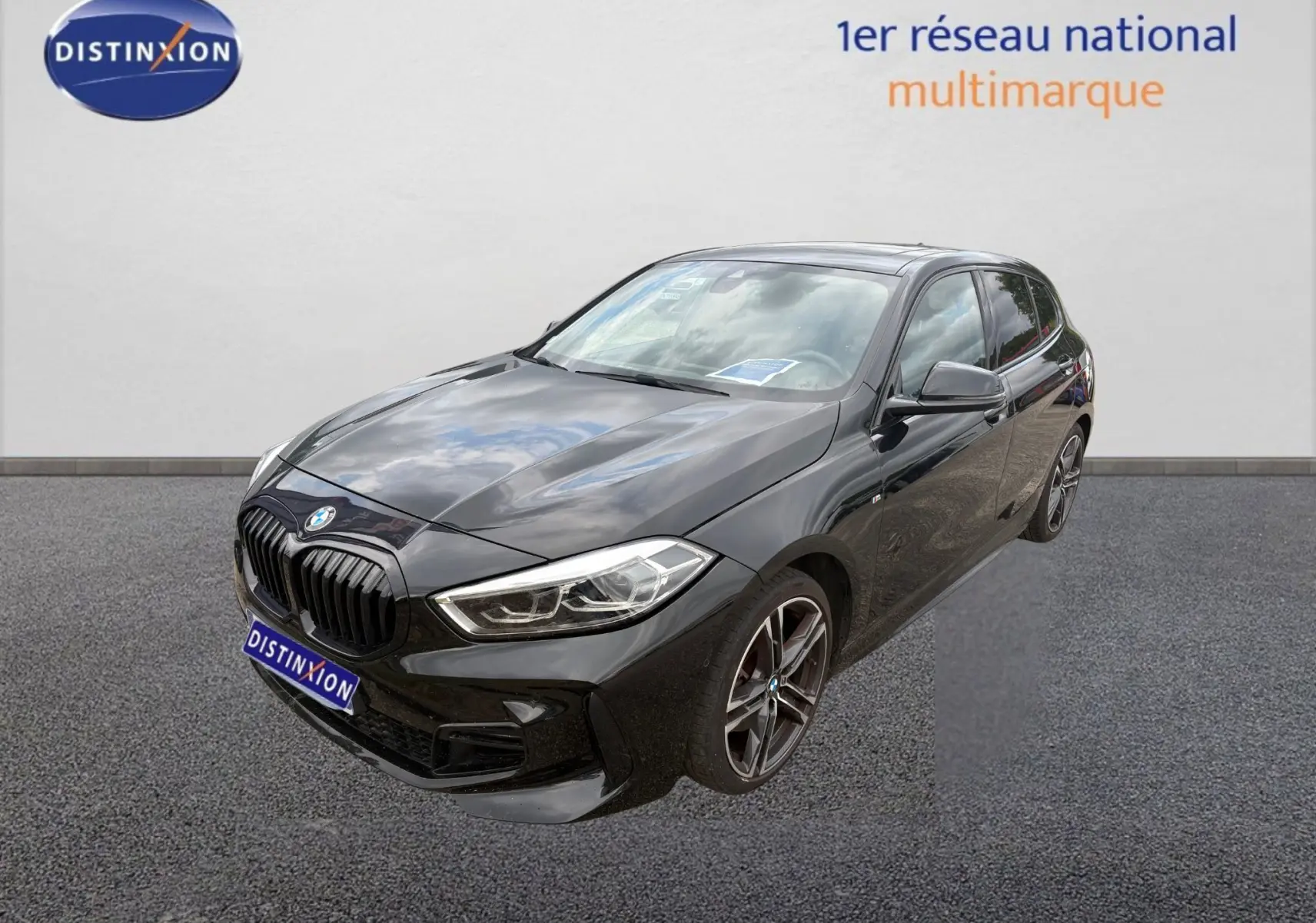 Vue arrière d'une BMW Série 1 noire 116d M Sport avec attelage et feux arrière LED allumés.