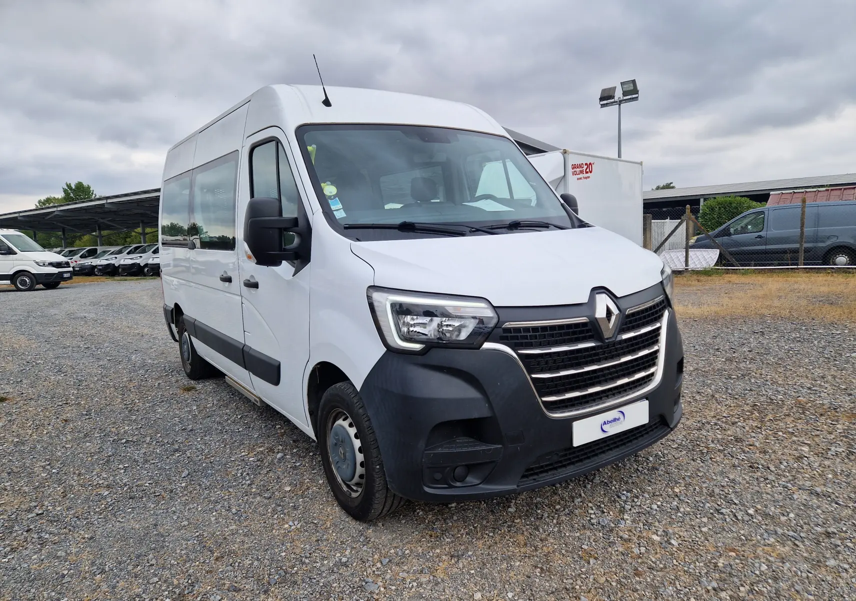 Renault Master blanc en 3/4 avant droit, utilitaire avec large pare-chocs noir et grandes vitres latérales.