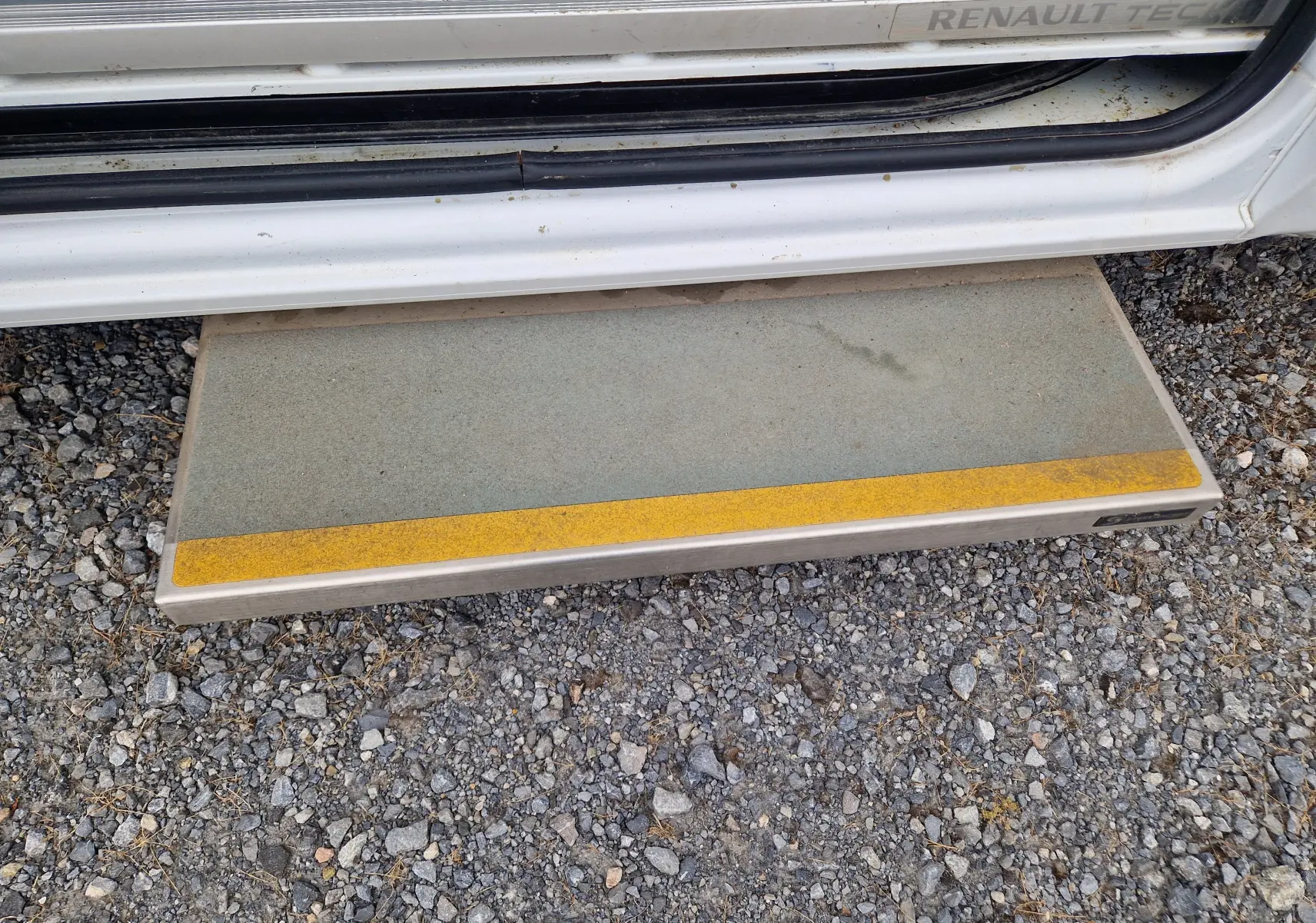 Marchepied latéral gris avec bande jaune sur Renault Master blanc, vue rapprochée de la porte ouverte côté droit.