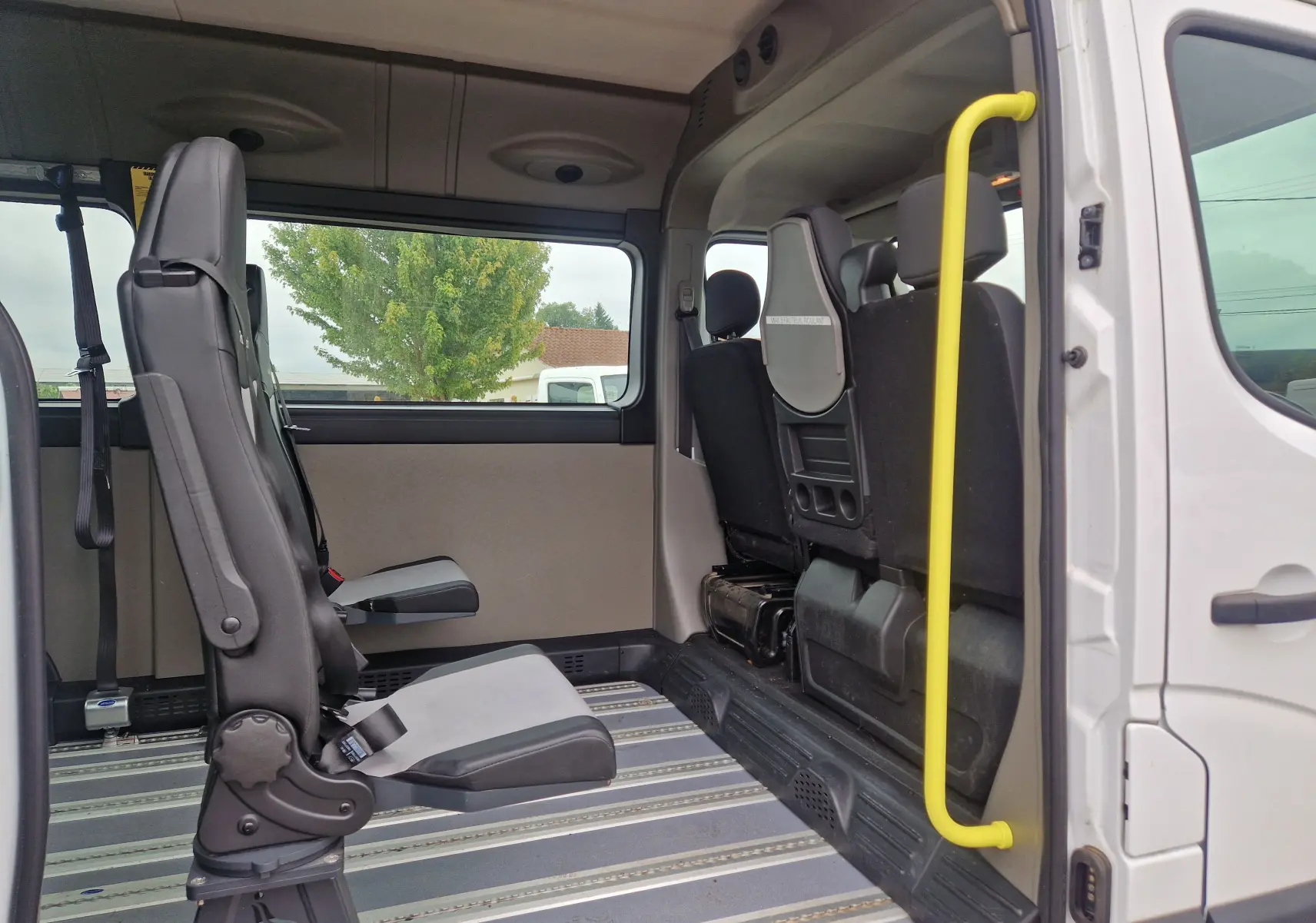 Vue intérieure côté droit du Renault Master blanc 2020 TPMR, montrant les sièges passagers et la barre d’appui jaune.