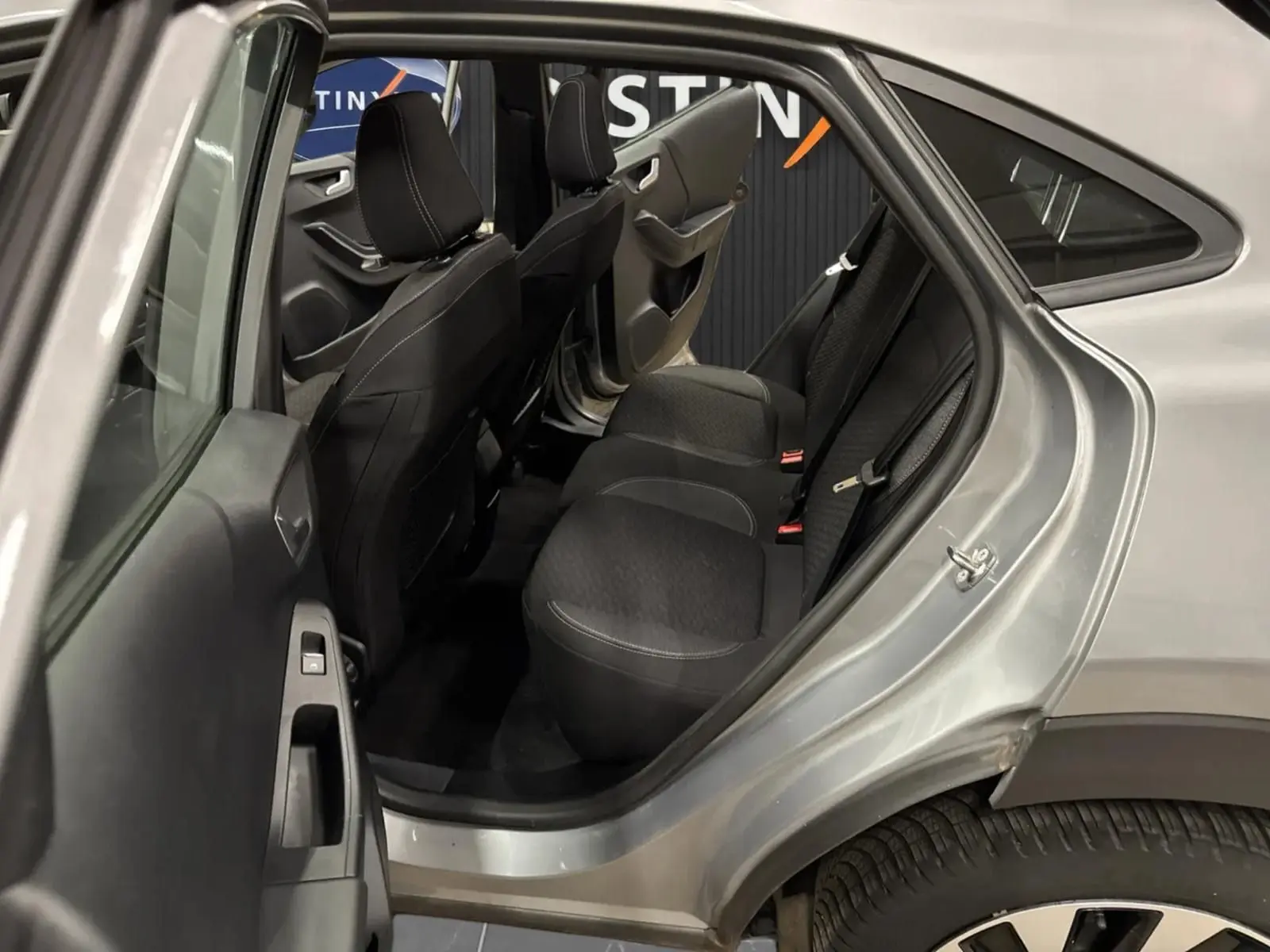 Vue côté gauche arrière du Ford Puma gris Solar 2023, montrant l'intérieur avec sièges arrière en tissu noir.