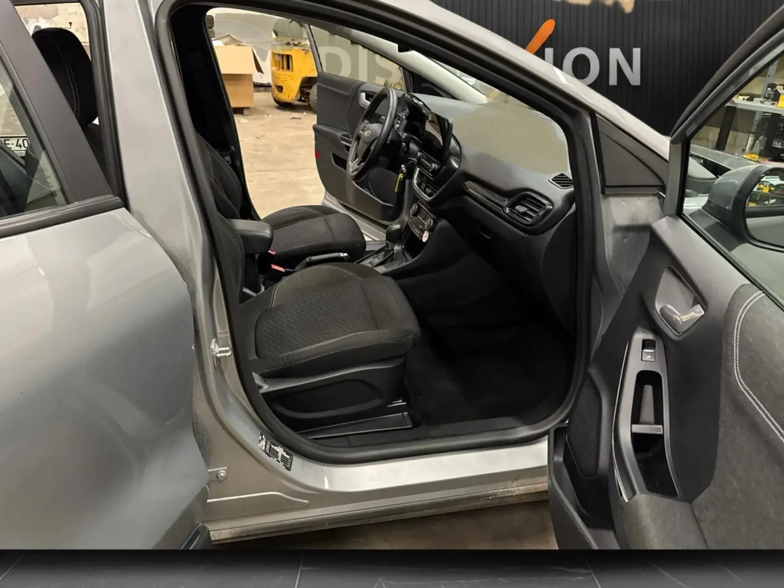 Vue intérieure côté conducteur du Ford Puma gris solar 2023, montrant sièges noirs et tableau de bord moderne.