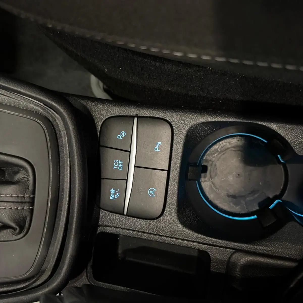 Gros plan sur la console centrale du Ford Puma gris Solar 2023, avec boutons de contrôle et porte-gobelet éclairé.