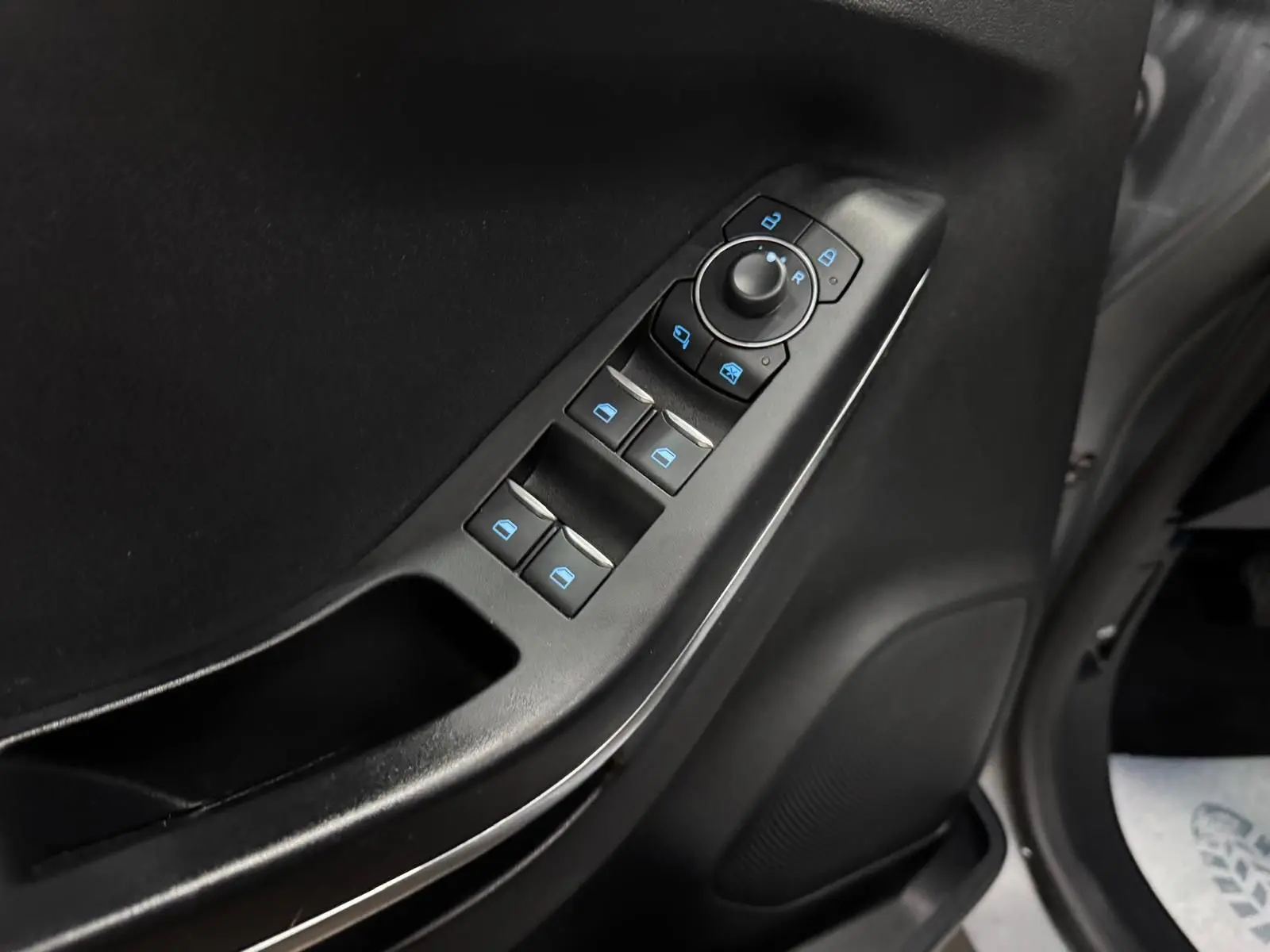 Gros plan sur les commandes de lève-vitres et rétroviseurs côté conducteur du Ford Puma gris Solar 2023.