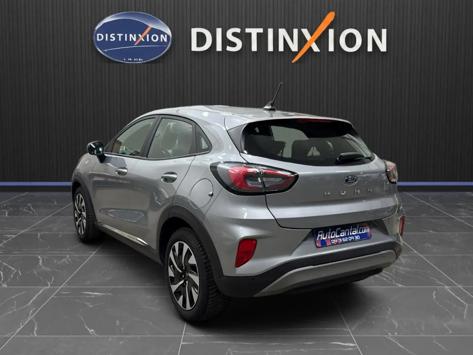 Vue 3/4 arrière droite d'un Ford Puma gris solar 2023 avec feux LED et jantes alliage 17 pouces dans un showroom.