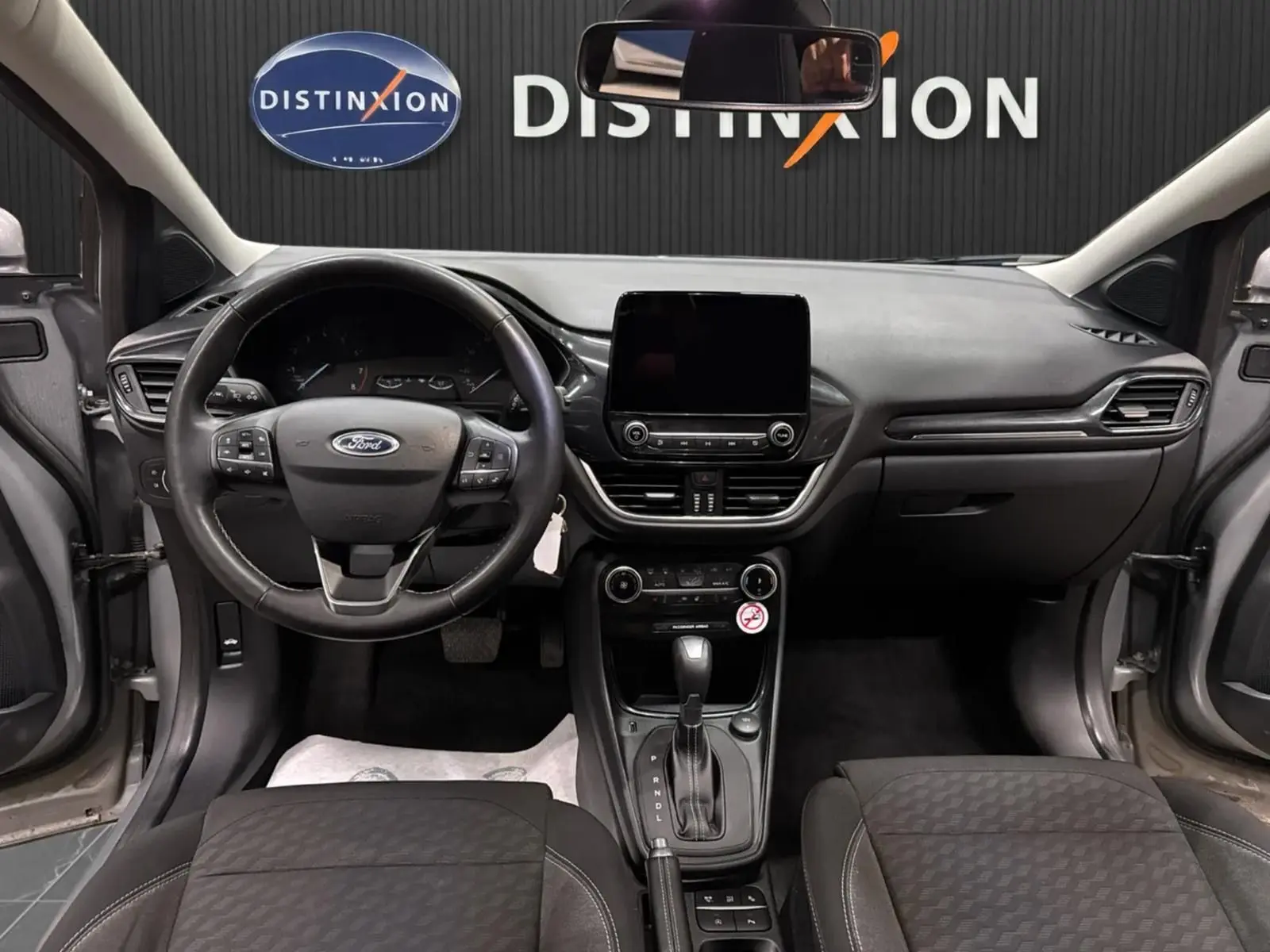 Vue intérieure frontale du tableau de bord et volant du Ford Puma gris Solar, avec écran tactile et boîte automatique visible.