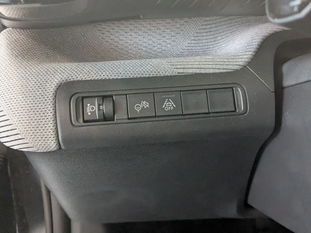 Gros plan sur les commandes de réglage des phares et aides à la conduite dans l’habitacle du Citroën E-C3 Aircross noir 2025.