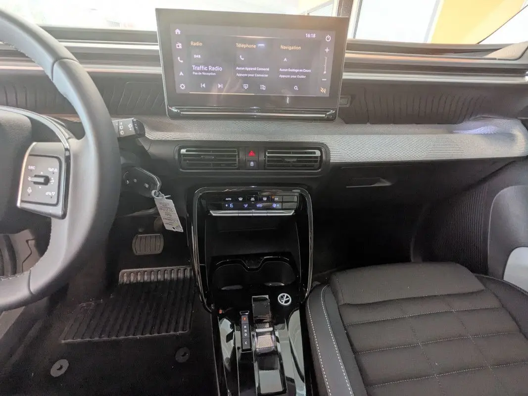 Vue intérieure centrée sur la console et le tableau de bord noir du Citroën E-C3 Aircross 2025 avec écran tactile et sellerie TEP/tissu.