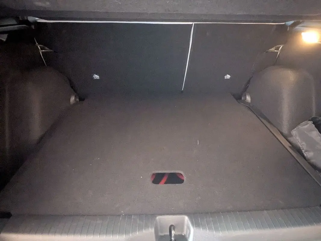 Coffre ouvert en vue arrière d'une Citroën E-C3 Aircross 2025 noire, avec plancher plat et éclairage intérieur.
