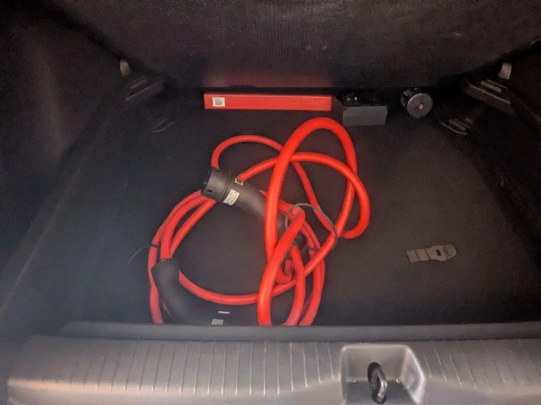 Coffre ouvert d’une Citroën E-C3 Aircross 2025 noir, montrant un câble de recharge électrique rouge enroulé.