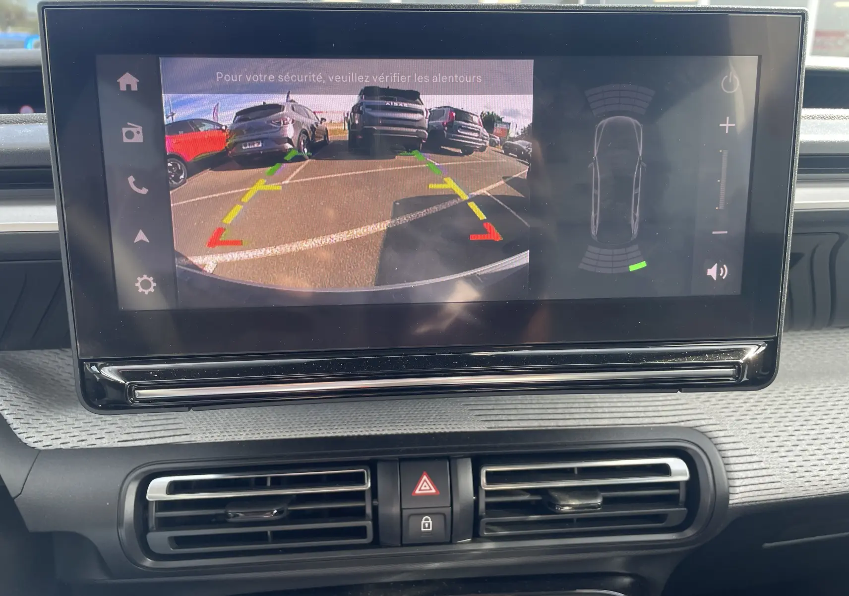 Écran central du tableau de bord du Citroën E-C3 Aircross 2025 montrant la caméra de recul avec guidage et capteurs de stationnement.