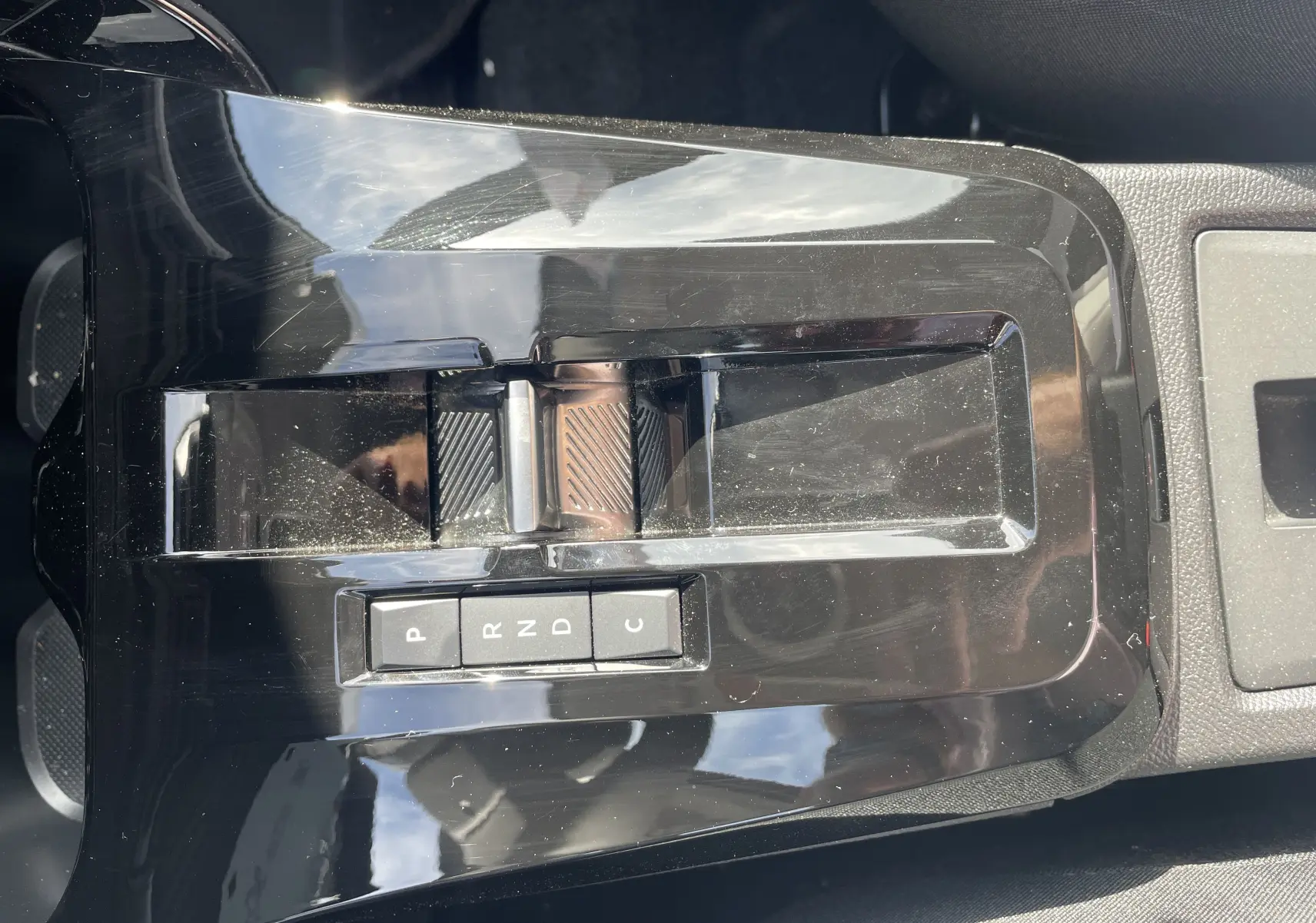 Gros plan sur la console centrale noire brillante du Citroën E-C3 Aircross 2025 avec levier de vitesses automatique et boutons P, R, N, D, C.