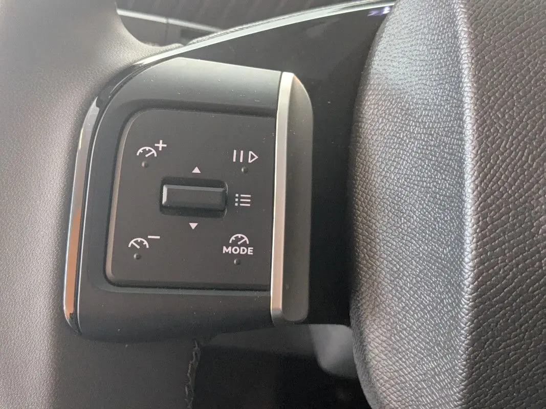 Gros plan sur les commandes au volant du Citroën E-C3 Aircross 2025, avec finition noire et boutons de régulateur de vitesse.