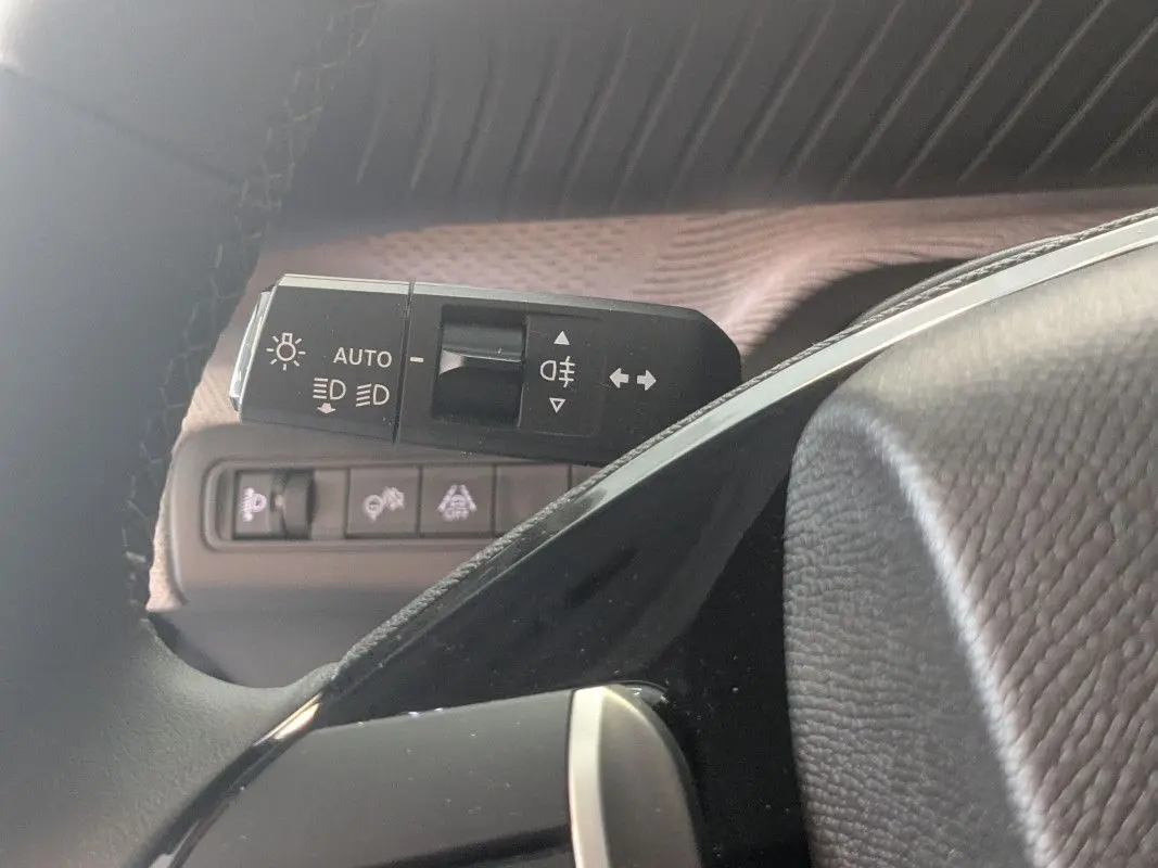 Gros plan sur la commande des feux automatiques et clignotants côté gauche du volant d’une Citroën C3 Aircross noire.