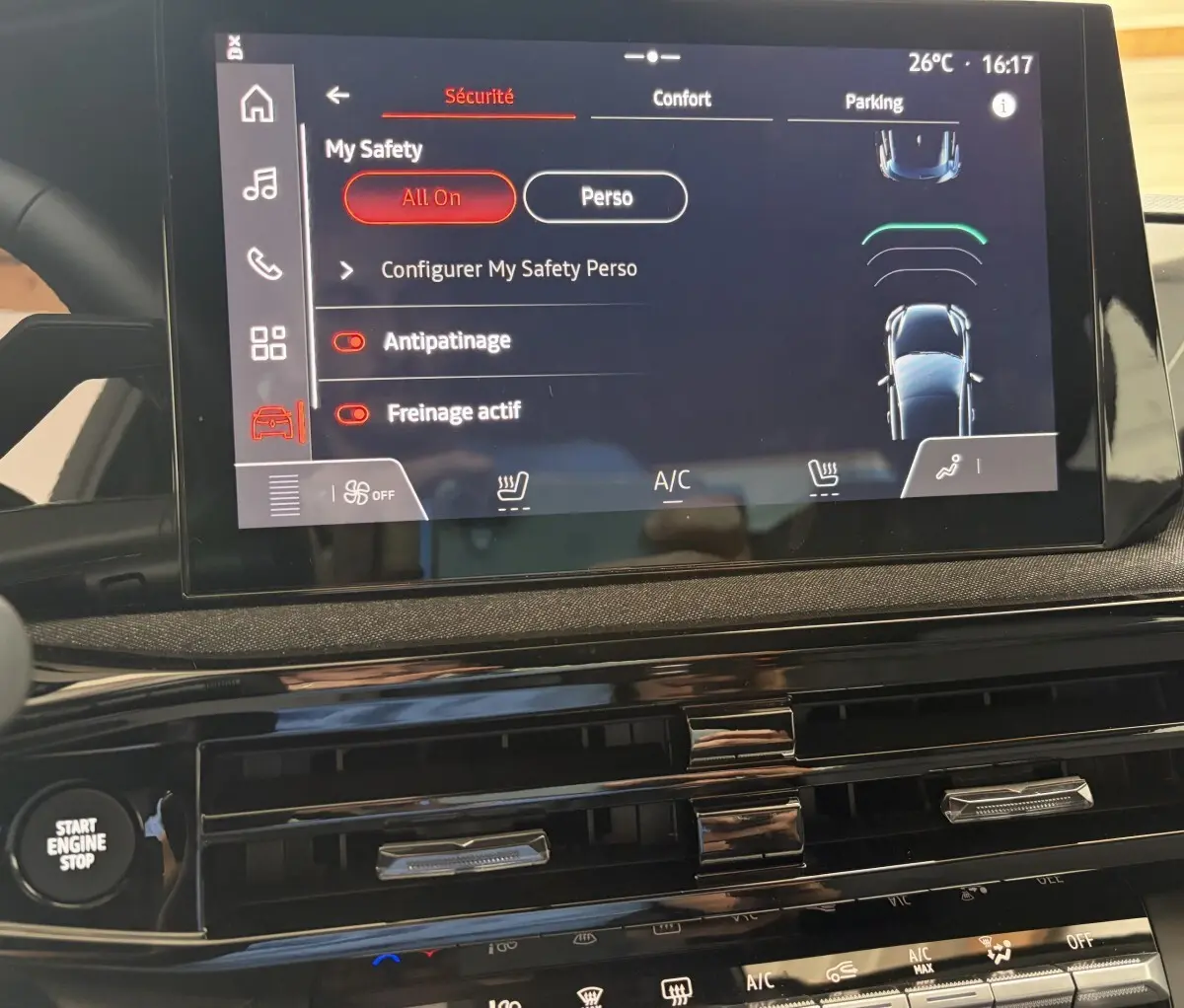Vue rapprochée de l’écran tactile central de la Renault Clio rouge 2025, affichant les réglages de sécurité et confort.