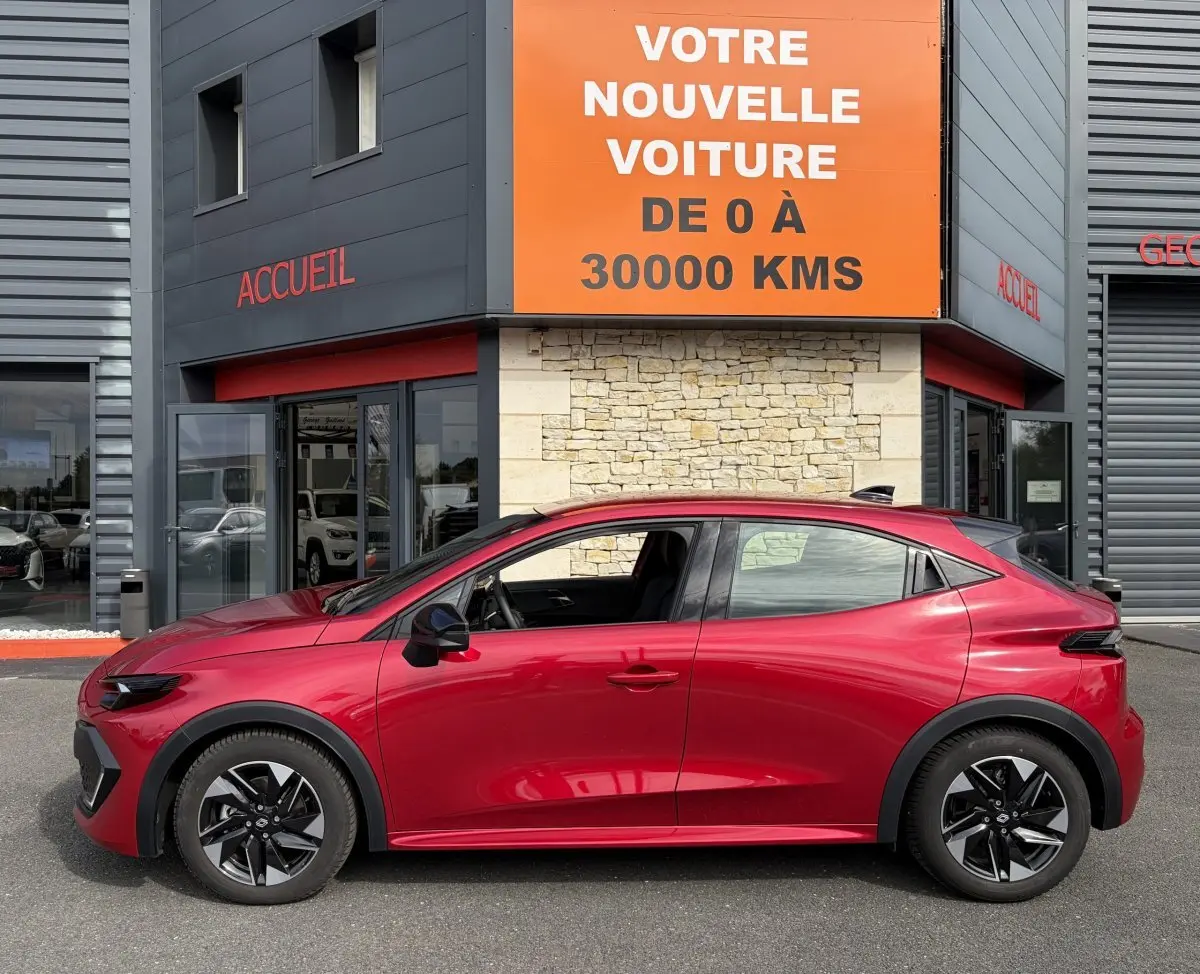 Profil côté gauche de la Renault Clio Evolution rouge 2025, hybride essence, avec jantes noires distinctives.