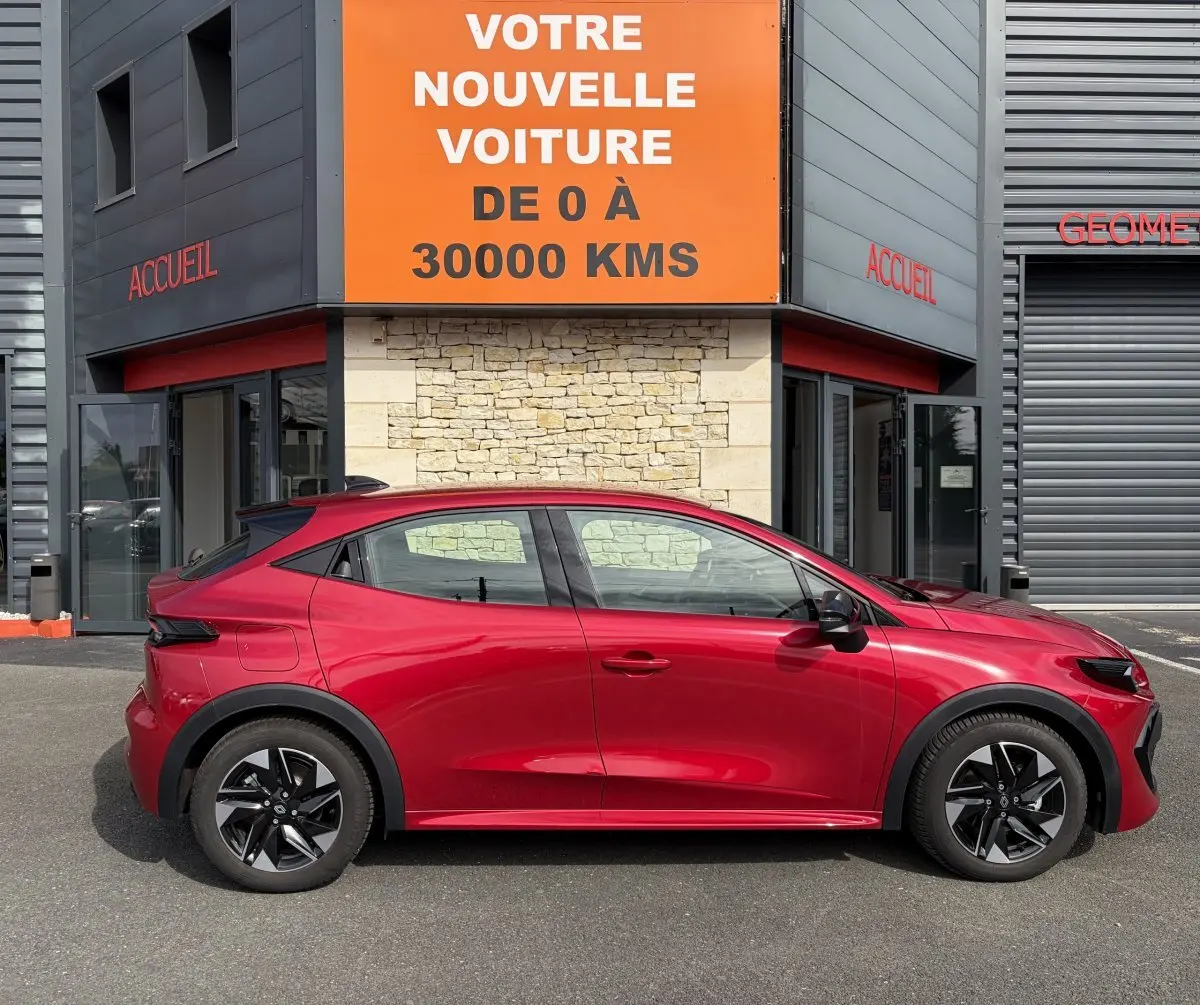 Profil côté gauche de la Renault Clio Evolution rouge 2025, hybride essence, avec jantes noires distinctives.
