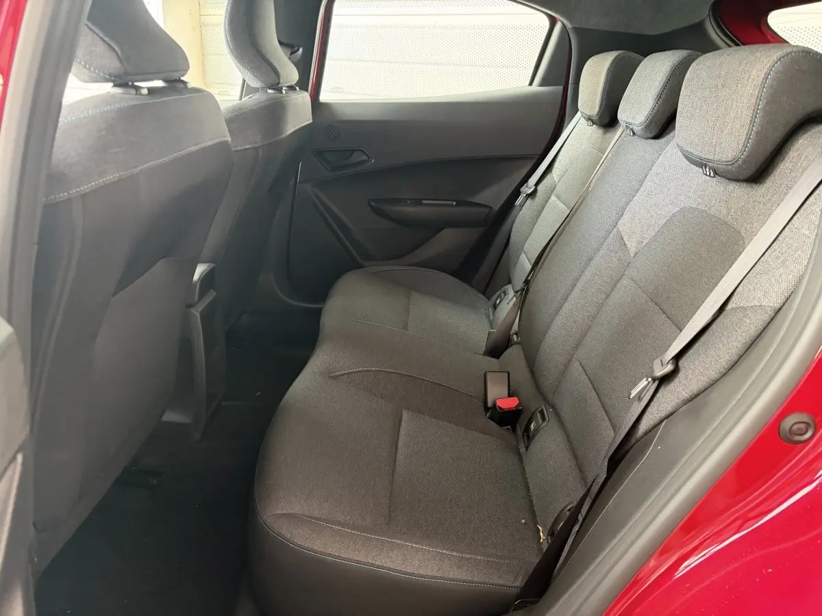 Vue intérieure côté droit sur la banquette arrière grise de la Renault Clio rouge 2025 hybride E-Tech.