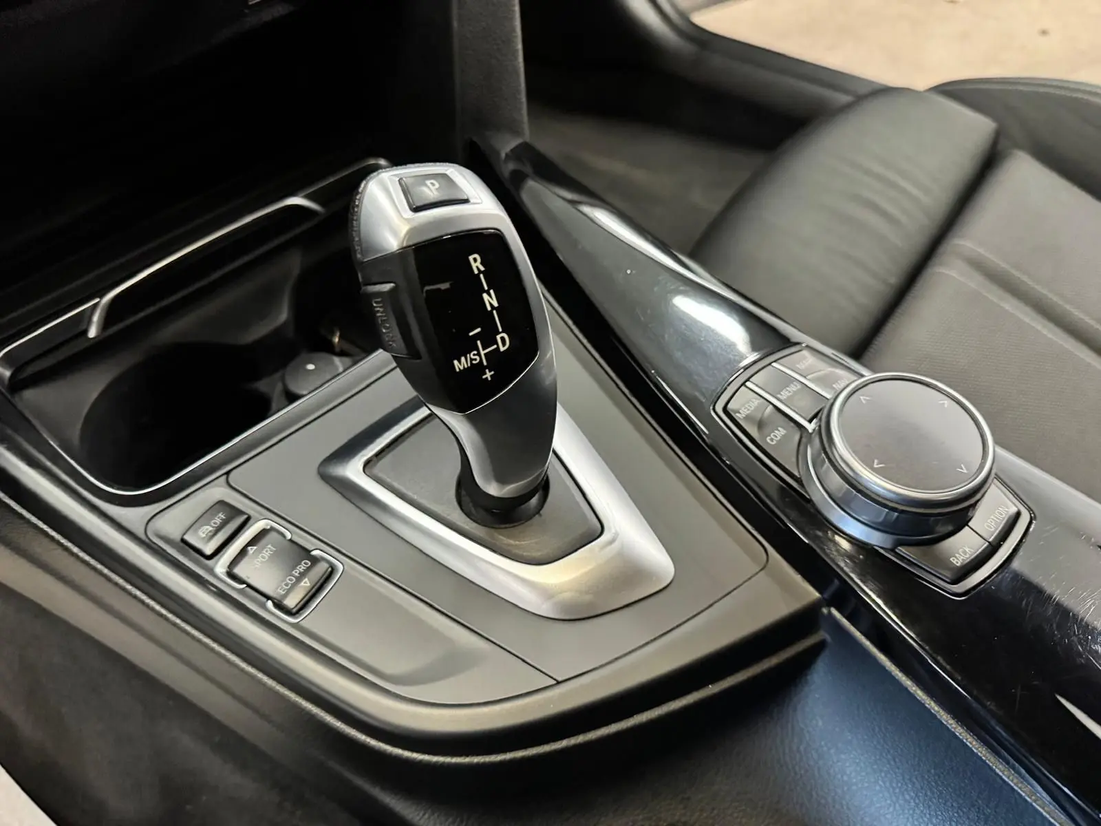 Gros plan sur la console centrale noire de la BMW Série 3 Touring F31 avec levier de vitesse automatique et molette de commande.