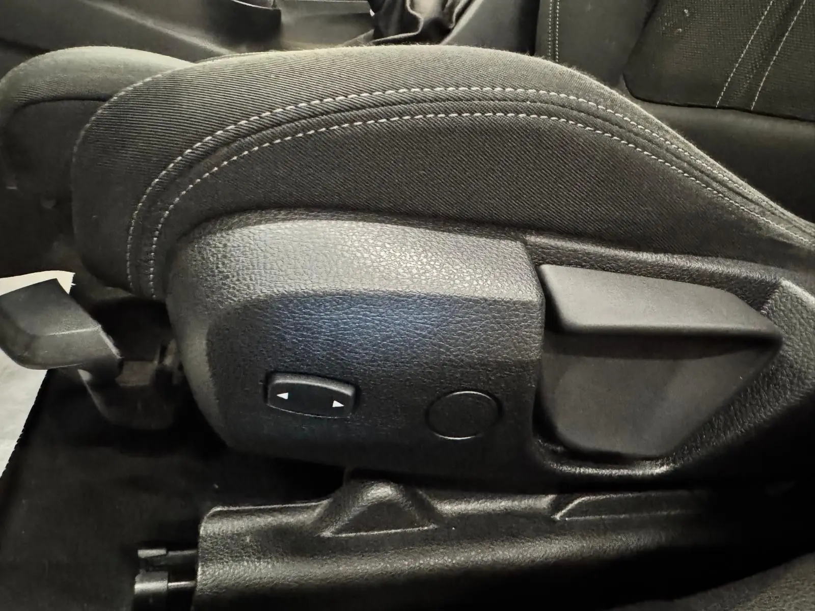 Gros plan sur les commandes latérales du siège avant en tissu noir de la BMW Série 3 Touring F31 gris aluminium.