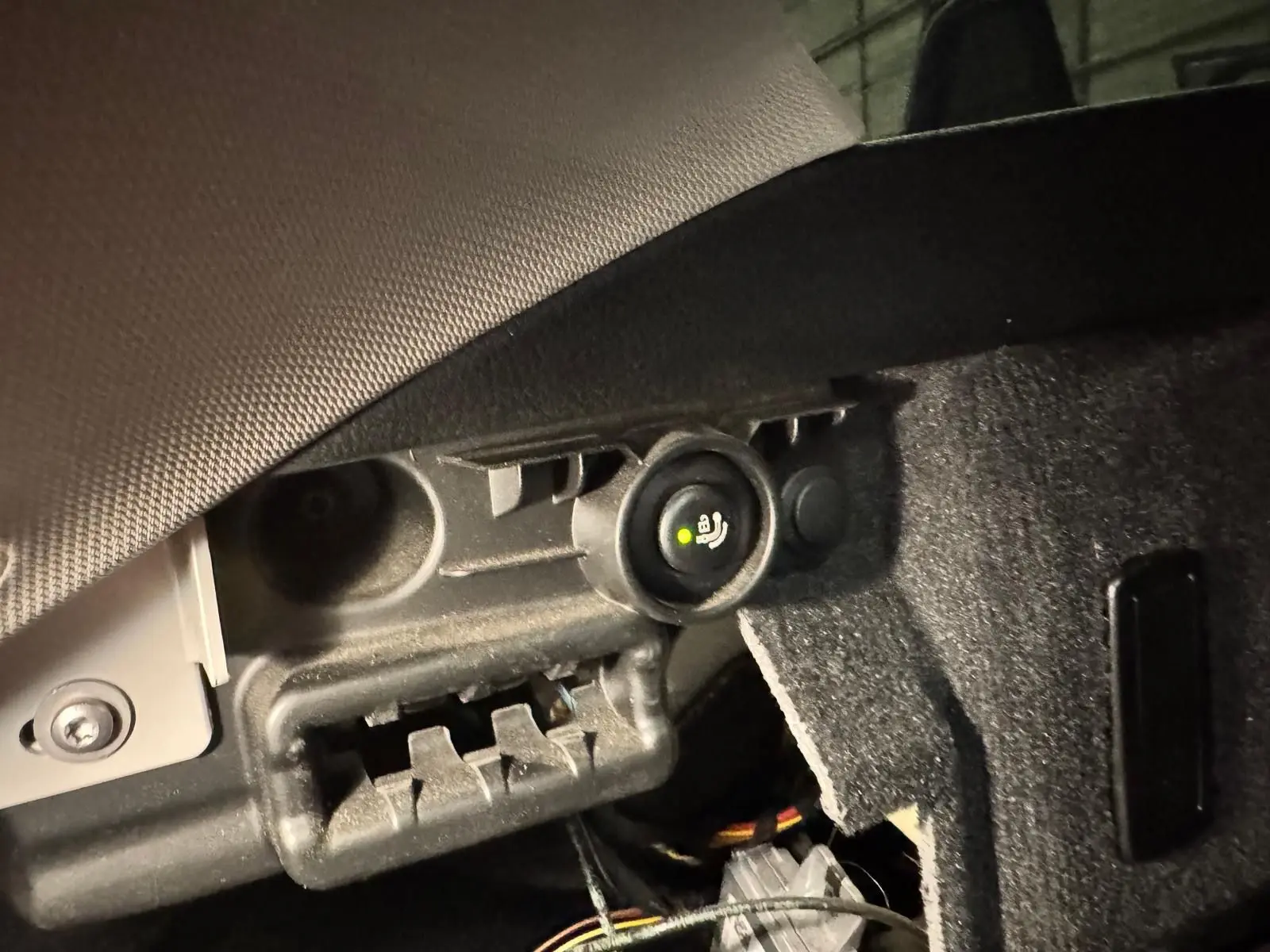 Détail de l'attelage électrique sous le coffre d'une BMW Série 3 Touring F31 gris aluminium, avec prise et bouton de commande.