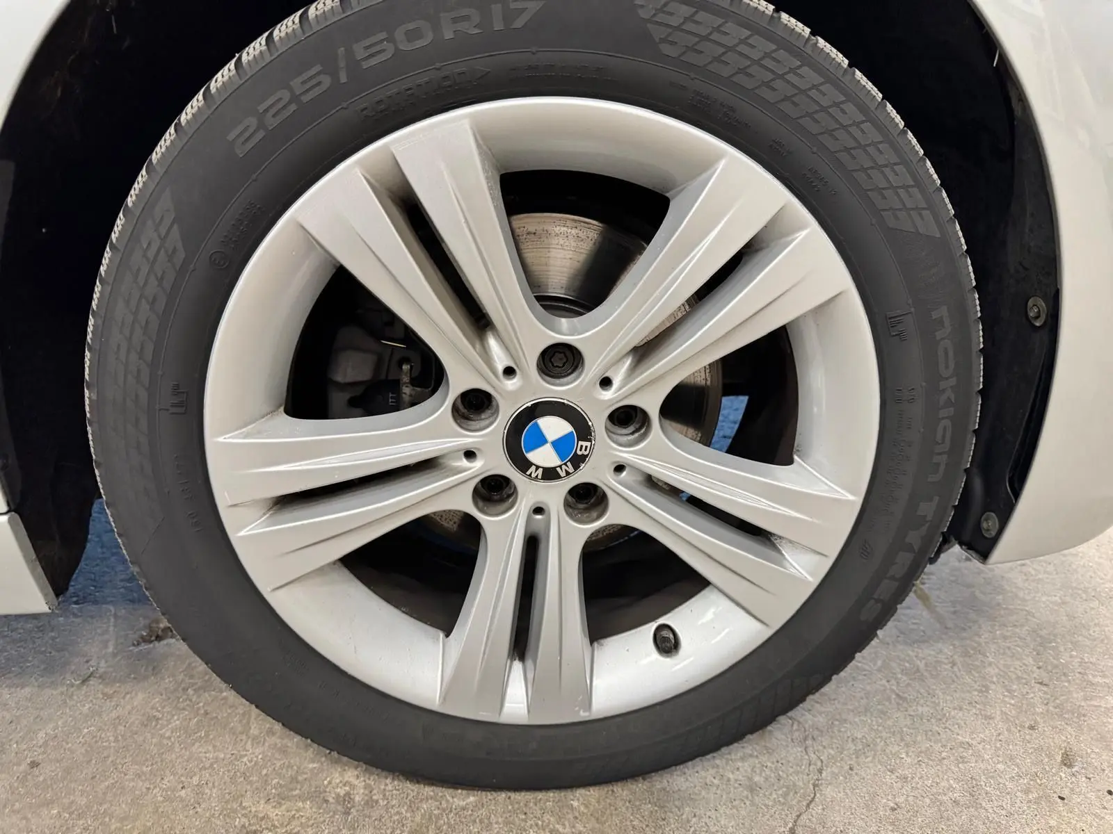 Gros plan sur la roue avant gauche avec jante alliage gris et pneu Nokian 225/50 R17 d’une BMW Série 3 Touring F31 gris aluminium.