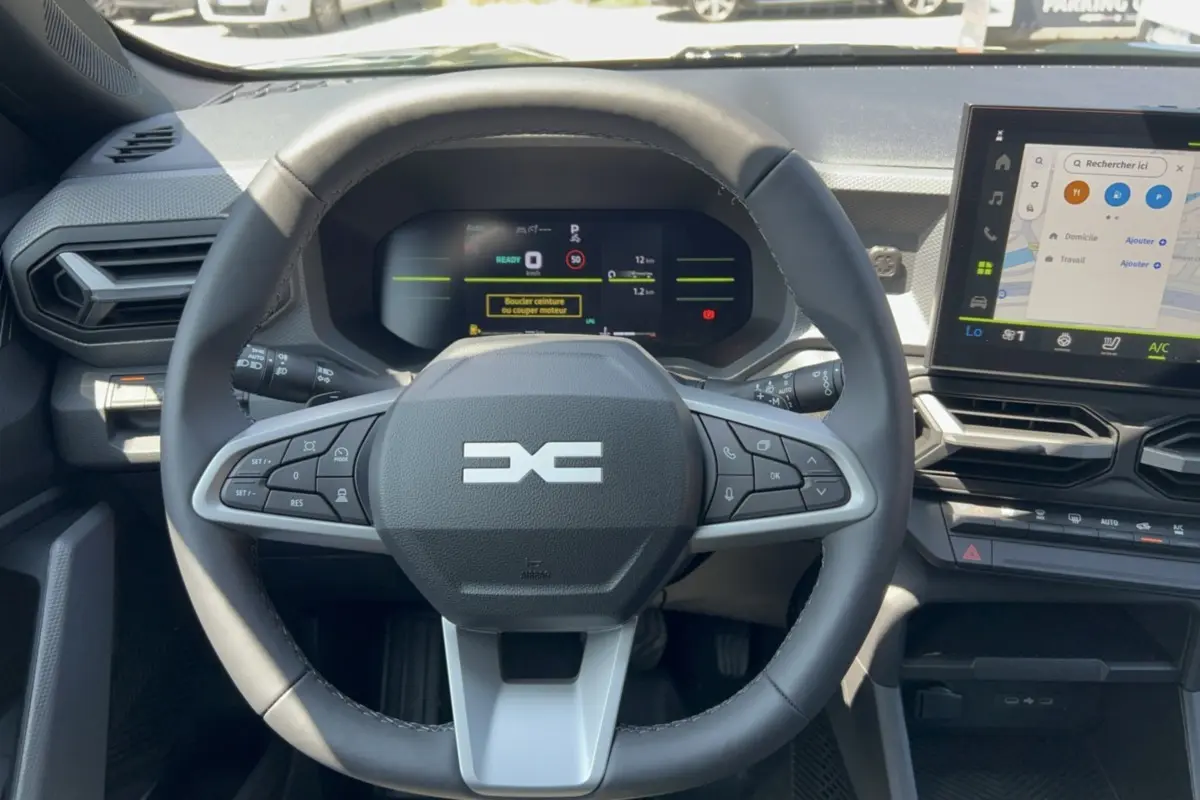 Vue intérieure centrée sur le volant cuir et le tableau de bord numérique du Dacia Duster Hybrid-G 2026.