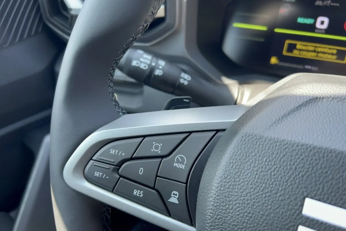 Gros plan sur les commandes de régulateur de vitesse au volant cuir du Dacia Duster Hybrid-G 150 4x4.