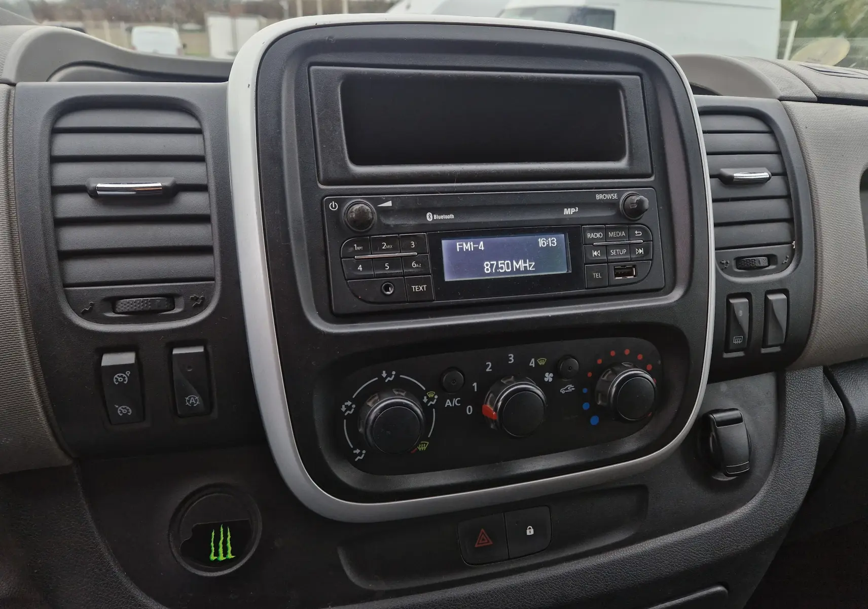 Tableau de bord du Renault Trafic Fourgon blanc, vue centrale sur la radio et les commandes de climatisation.