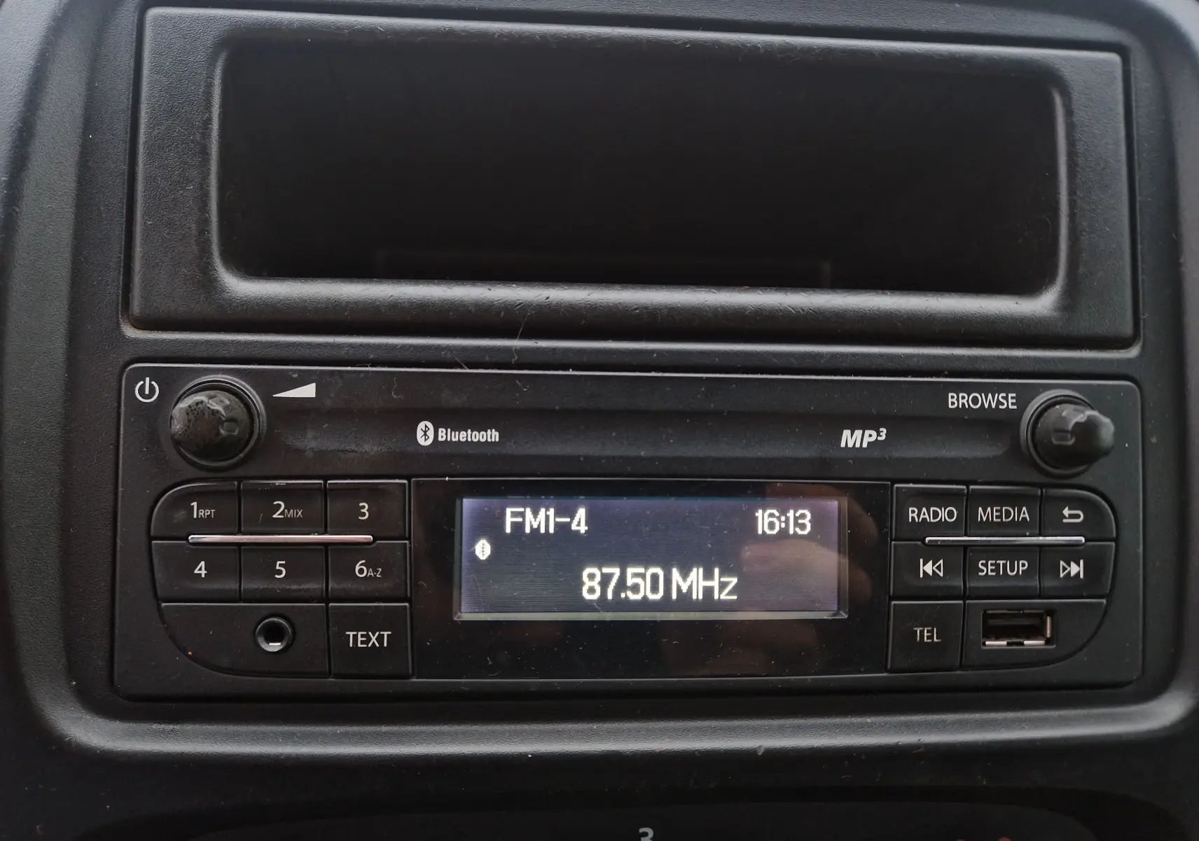 Gros plan sur la radio MP3 intégrée du Renault Trafic Fourgon blanc, affichant la fréquence FM 87.50 MHz.