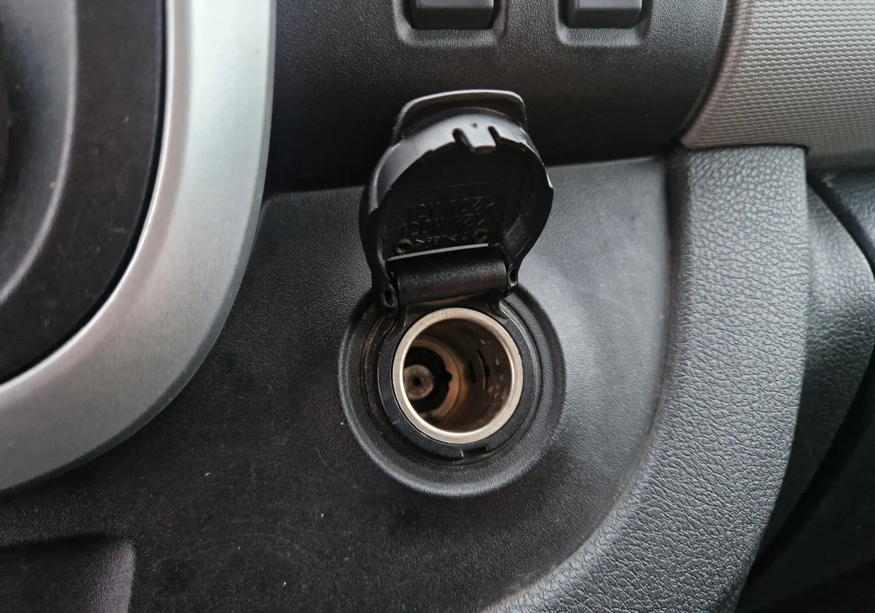 Prise allume-cigare ouverte sur le tableau de bord noir du Renault Trafic Fourgon blanc, version L1H1 2019.