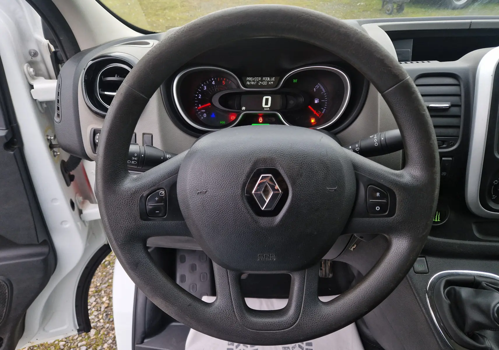 Vue intérieure centrée sur le volant noir du Renault Trafic blanc, tableau de bord et compteurs visibles derrière.