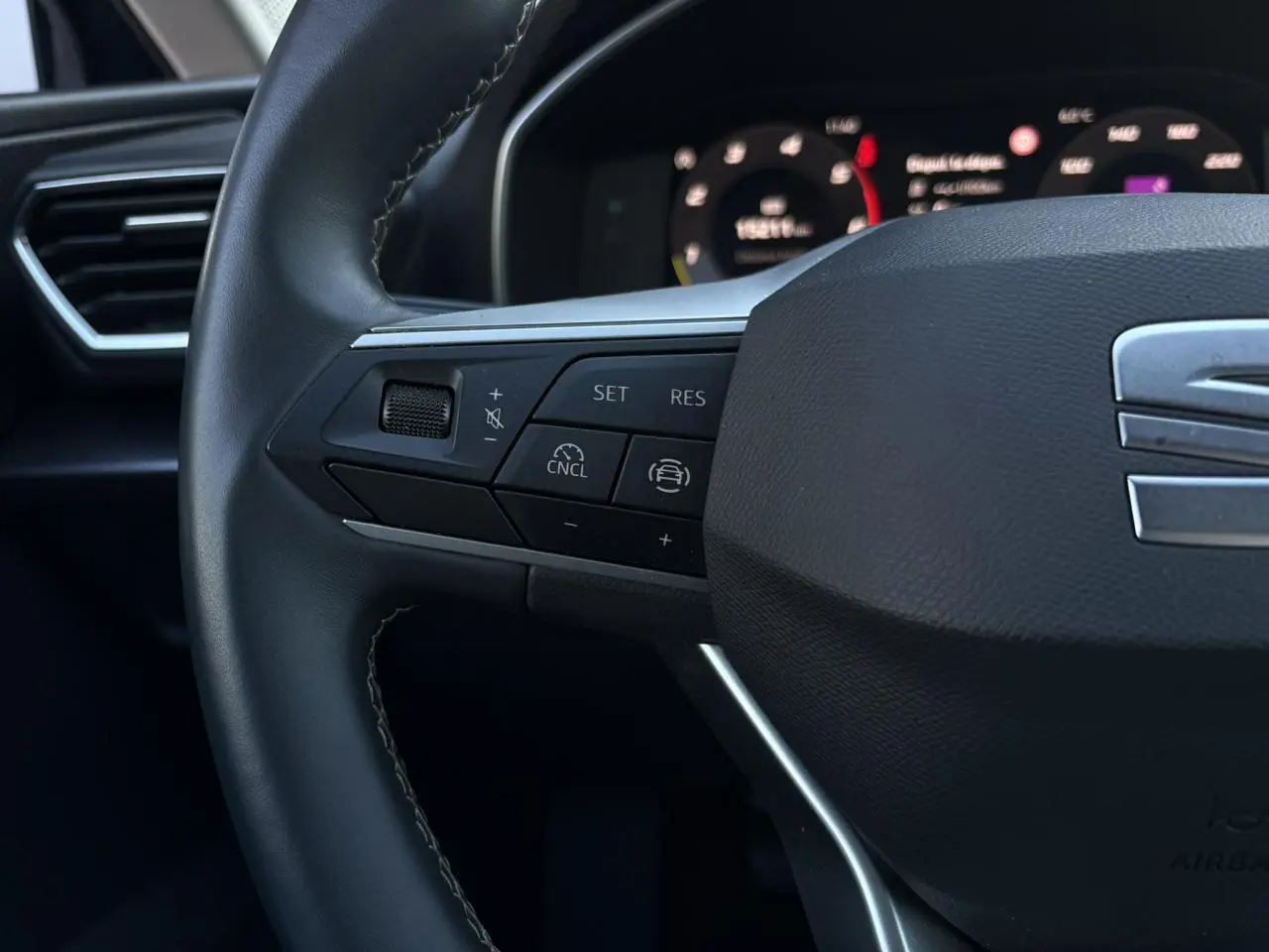 Gros plan sur le volant cuir multifonction de la SEAT LEON ST 2.0 TDI 115 Style avec commandes de régulateur de vitesse.