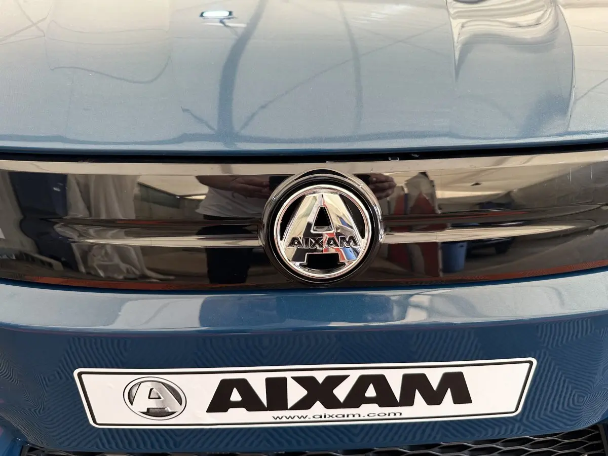 Gros plan avant sur la calandre bleue de l'AIXAM AMBITION 0.5 CITY PACK avec logo central et plaque constructeur.