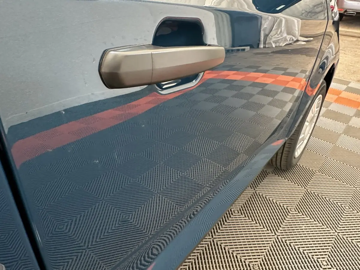 Gros plan sur la porte côté conducteur d'une Aixam Ambition 0.5 City Pack bleu, mettant en valeur le rétroviseur caméra.