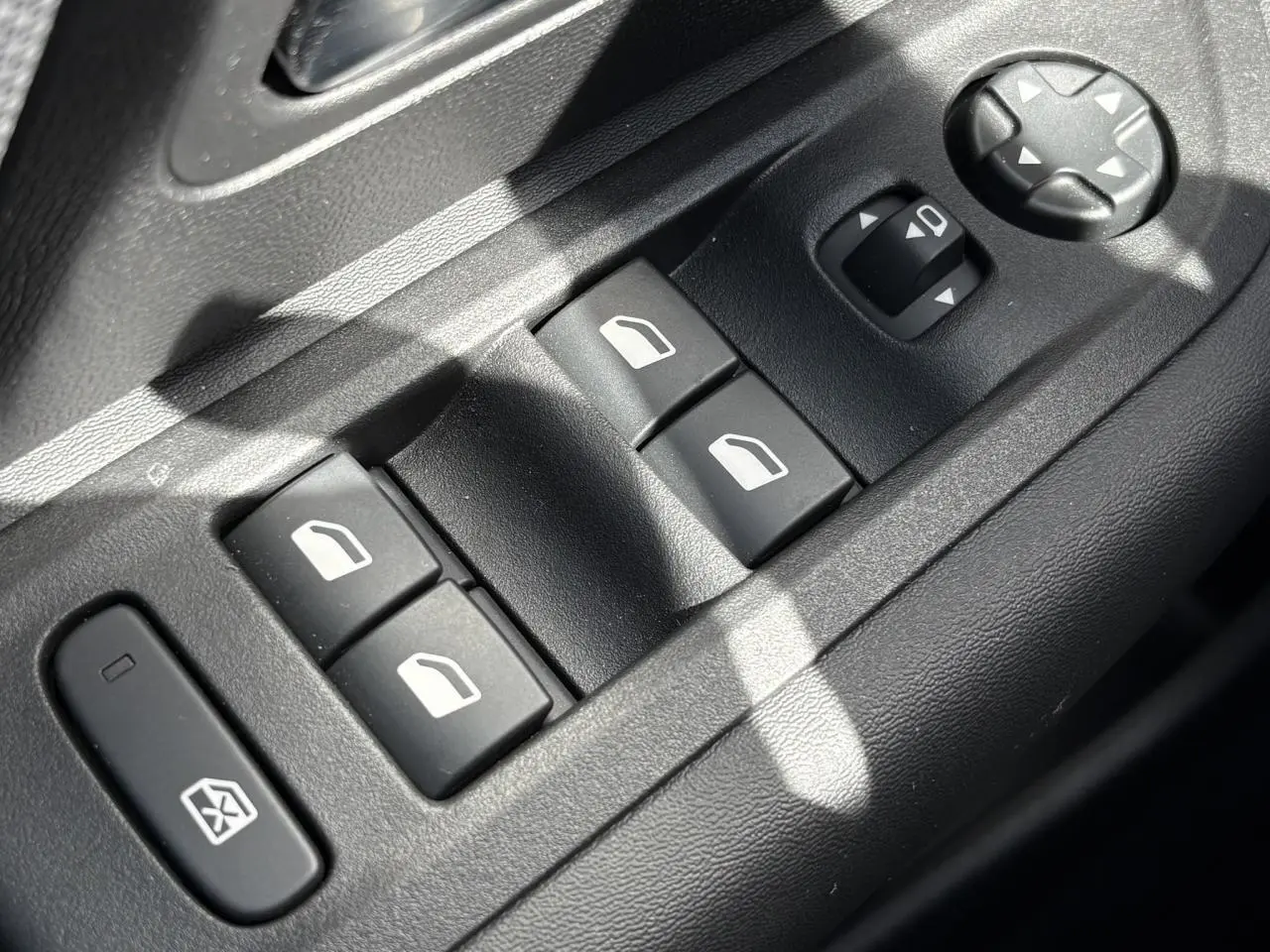 Gros plan sur les commandes de lève-vitres et réglage des rétroviseurs côté conducteur d'une Citroën C4 Hybrid 2025.