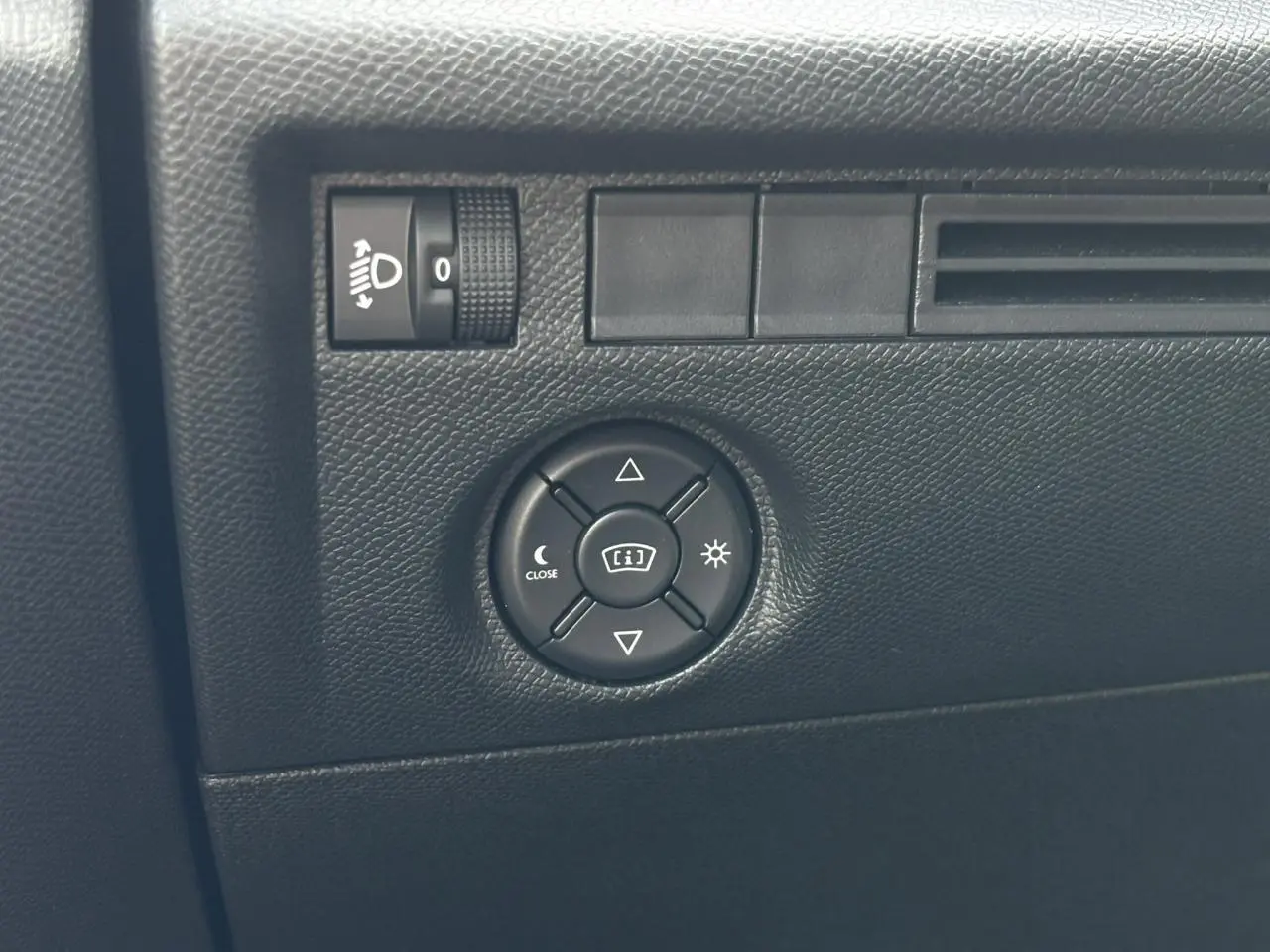 Gros plan sur les commandes d’éclairage et réglage du tableau de bord dans l’habitacle noir du Citroën C4 Hybrid 2025.