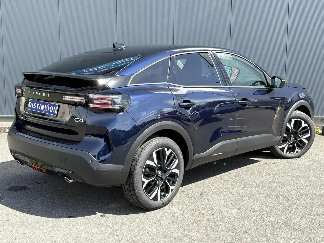 Vue 3/4 arrière droite d'une Citroën C4 Hybrid 145 bleu Eclipse avec jantes alliage 18'' et toit noir brillant.