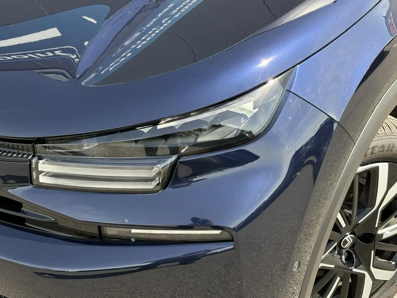 Gros plan sur l'avant droit bleu Eclipse du Citroën C4 Hybrid 2025 avec phares LED et jante alliage 18 pouces.